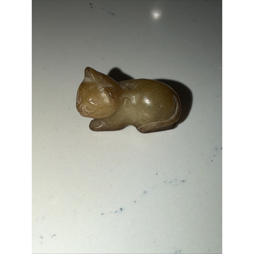 small, hand-carved stone or glass figurine of a resting cat,
